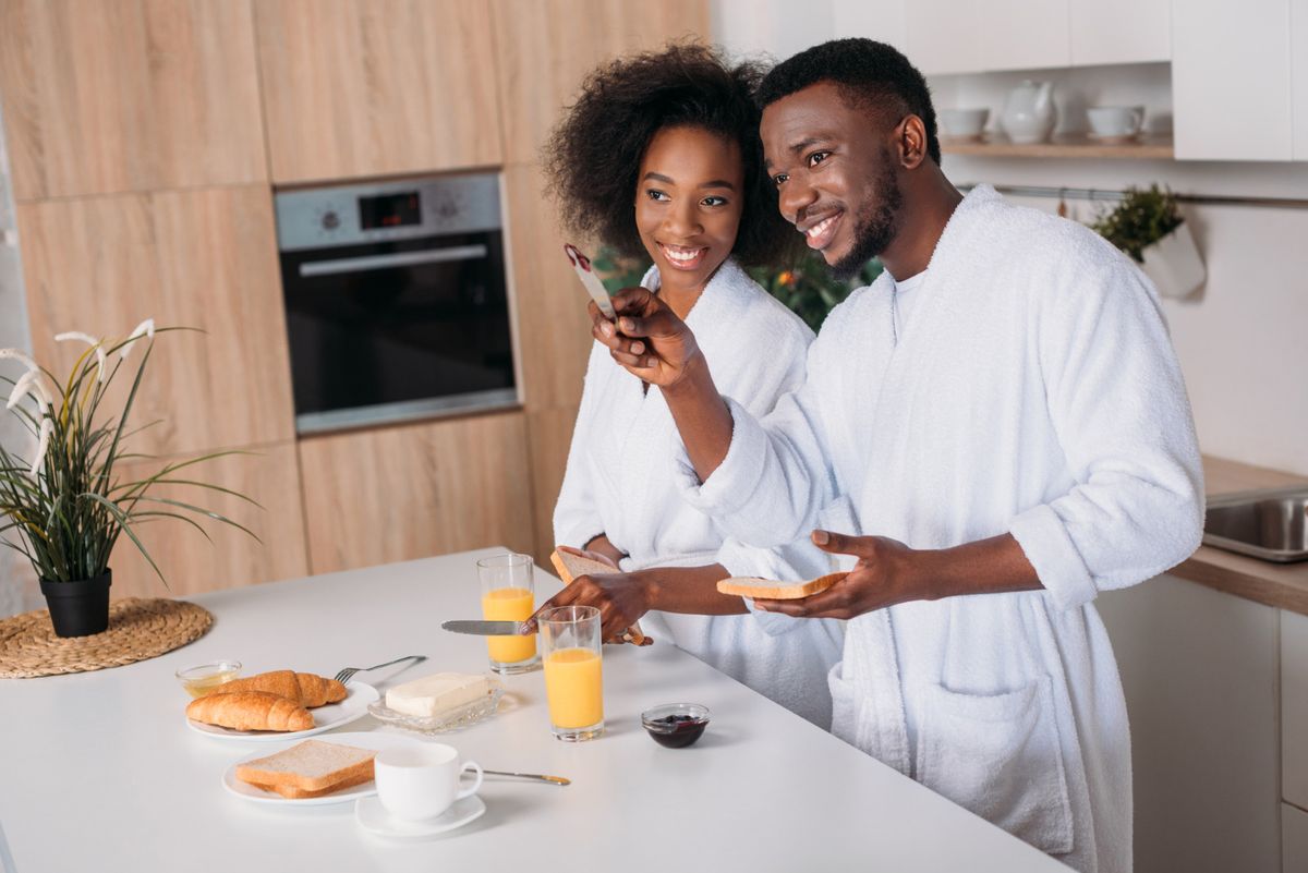 Un couple rit en préparant le petit-déjeuner dans sa cuisine